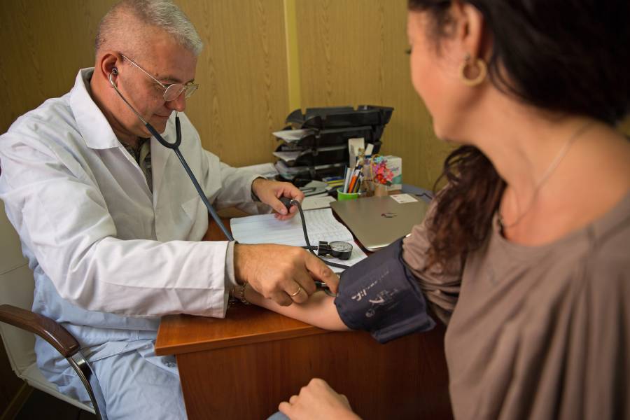 Ein Arzt mißt den Blutdruck einer Frau.
