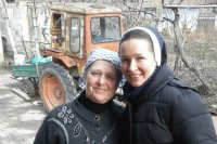 Schwester Antonia steht mit einer Frau vor einem Traktor.