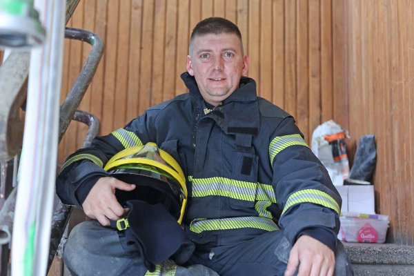 Der Feuerwehrmann Jovica Vučinić sitzt in Uniform auf einem Stuhl, den Helm trägt er in der Hand.