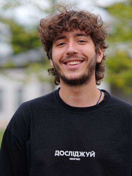 Porträt-Foto des Studenten Yurii Sckola. Er hat lockige, braune Haare, einen Bart und trägt ein schwarzes Sweat-Shirt.