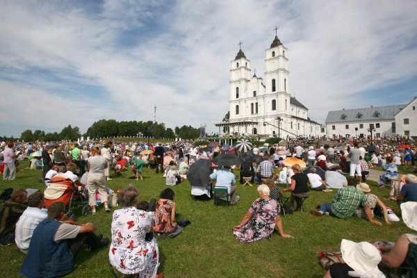 Menschen sitzen auf einer Wiese vor einer Wallfahrtskirche.