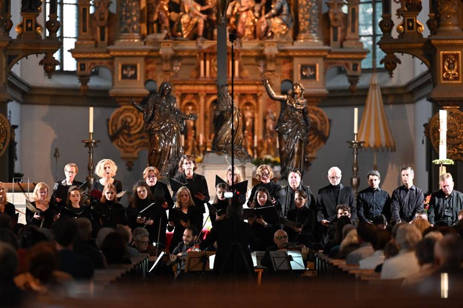 Das Foto zeigt die Musikerinnen und Musiker, die am Pfingstsamstag im Rahmen des Renovabis-Benefizkonzertes das Werk „Stabat Mater für Mariupol" aufgeführt haben. Sie tragen alle dunkle Kleidung und stehen in der dunklen Basilika Sankt Ulrich und Afra.