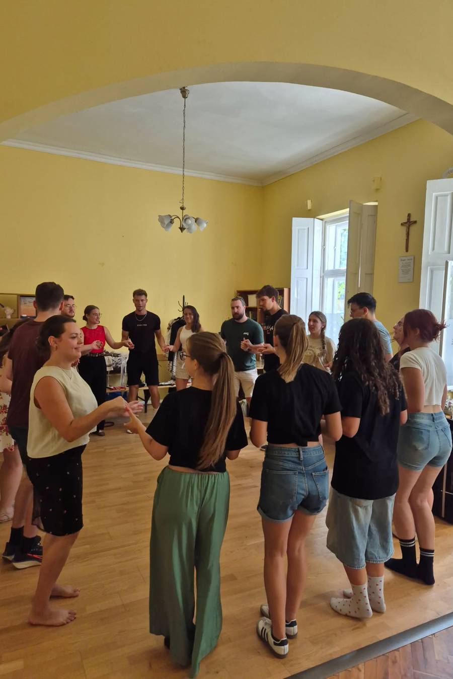 Eine Gruppe junger Leute beim gemeinsamen Tanz: Sie halten sich an den Händen und tanzen im Kreis.
