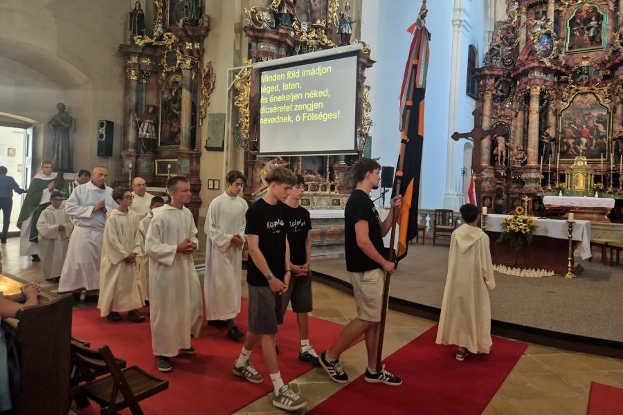 Eine Gruppe von jungen Menschen, Ministranten und einem Priester beim Einzug in eine Kirche