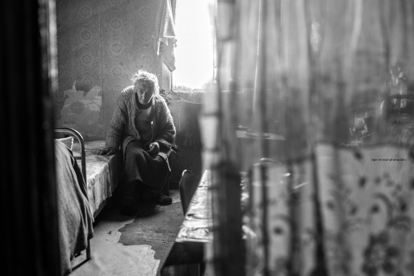 Schwarzweiß-Foto einer alten Frau in ihrem Zimmer