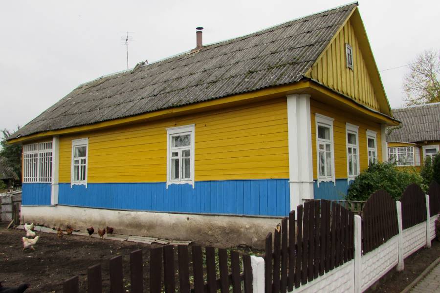 Gelb-blau gestrichenes Haus mit Hühnern
