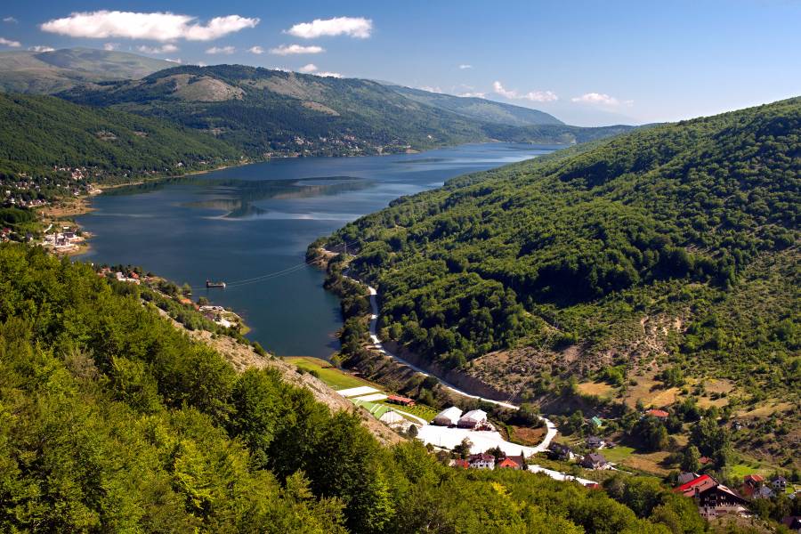 Ein dunkler Stausee, umgeben von Wäldern