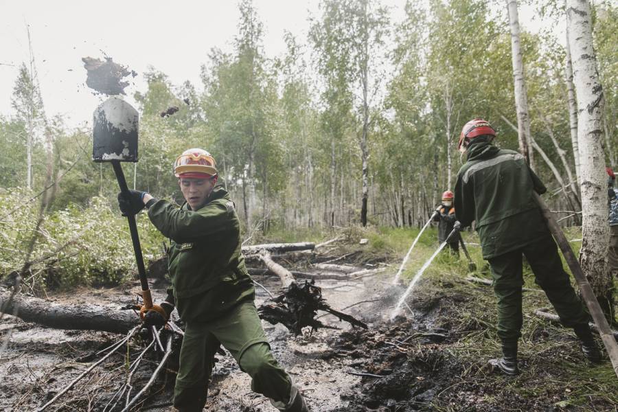 Maxim Schachko gräbt verbrannten Torf ab bei einem Torfbrand-Löscheinsatz.